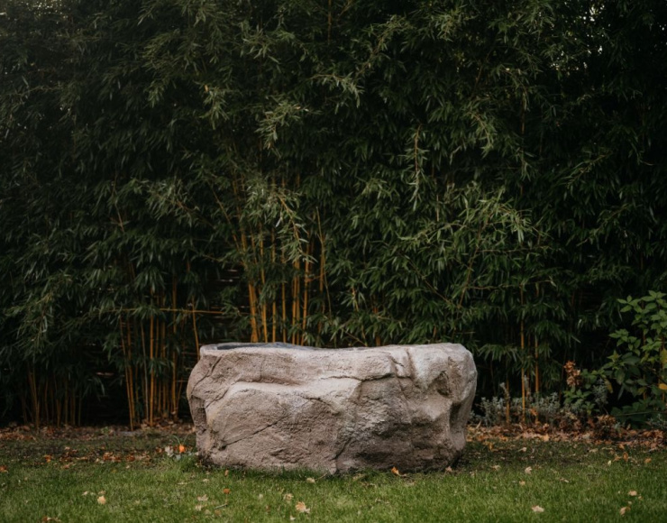 Oerbad® als sculpturaal betonnen bad, geplaatst in een natuurlijke tuinomgeving.