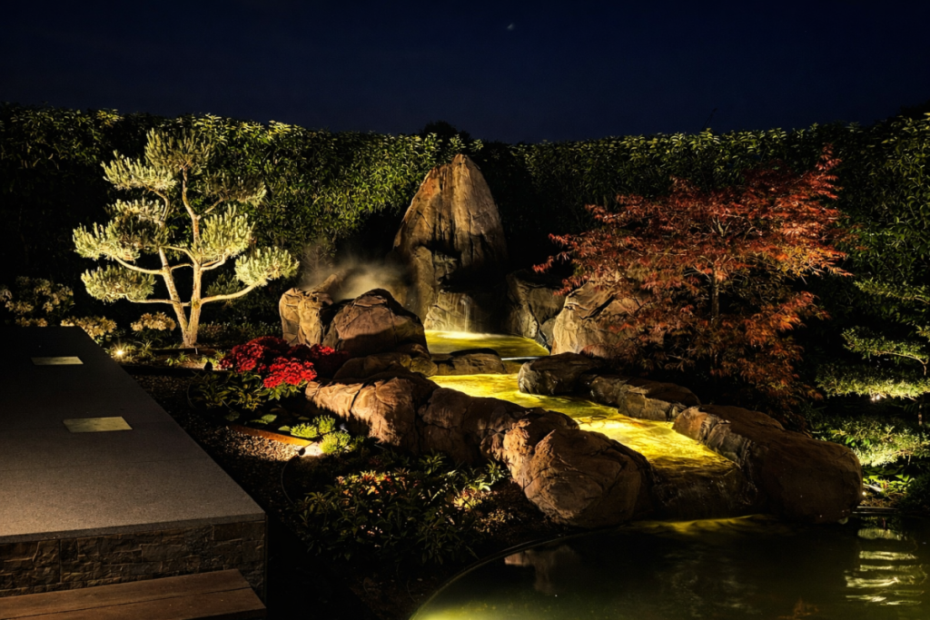 Avondbeeld van een sculpturaal waterlandschap met subtiel geïntegreerde verlichting.